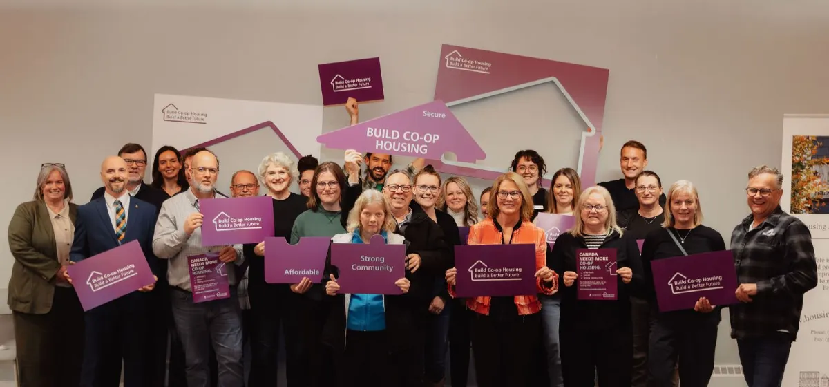A group of people holding purple signs about community housing features