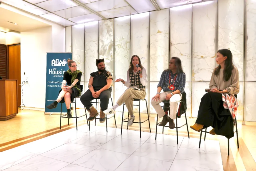A panel speaker holding a mic, with one hand open faced up