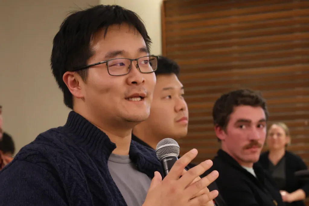 A man with glasses speaks with a mic in his hands