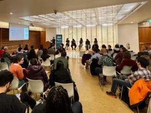 A room filled with people looking at speakers on stage